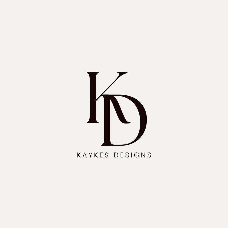 May include: A minimalist logo design featuring the intertwined letters "K" and "D" in a dark brown colour. Below the letters, the text "KAYKES DESIGNS" is displayed in a simple, sans-serif font against a cream background.