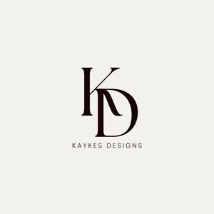 May include: A minimalist logo design featuring the intertwined letters "K" and "D" in a dark brown color. Below the letters, the text "KAYKES DESIGNS" is displayed in a simple, sans-serif font against a cream background.