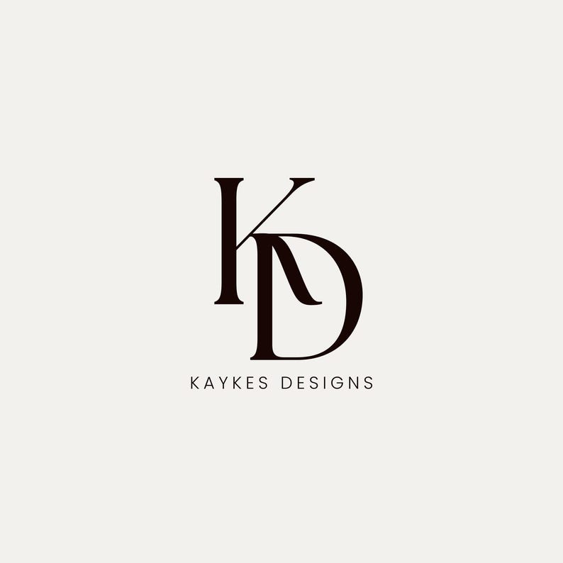 May include: A minimalist logo design featuring the intertwined letters "K" and "D" in a dark brown color. Below the letters, the text "KAYKES DESIGNS" is displayed in a simple, sans-serif font against a cream background.