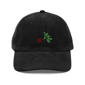 Puede incluir: Una gorra de béisbol de pana negra con un diseño bordado de bayas de acebo rojas y verdes.