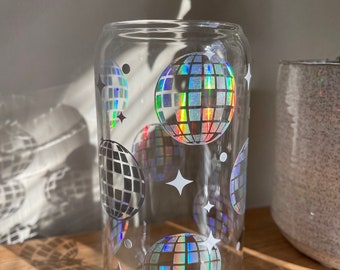May include: A clear glass drinking glass with a pattern of iridescent disco balls and white stars.