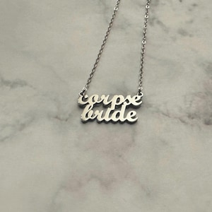 May include: Silver necklace with the words "corpse bride" written on it.