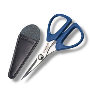 May include: Cutwork 115 Clover scissors with blue handles and silver blades, next to a black leather sheath with a gray stone. The scissors have the text "CUTWORK 115 CLOVER" printed on the blade.