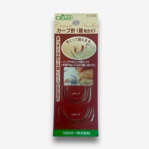 Puede incluir: Un paquete de agujas curvas Clover para coser. El paquete es rojo y blanco con texto japonés que dice "Clover Curved Needles". Las agujas se muestran en dos tamaños diferentes, tipo U y tipo C.