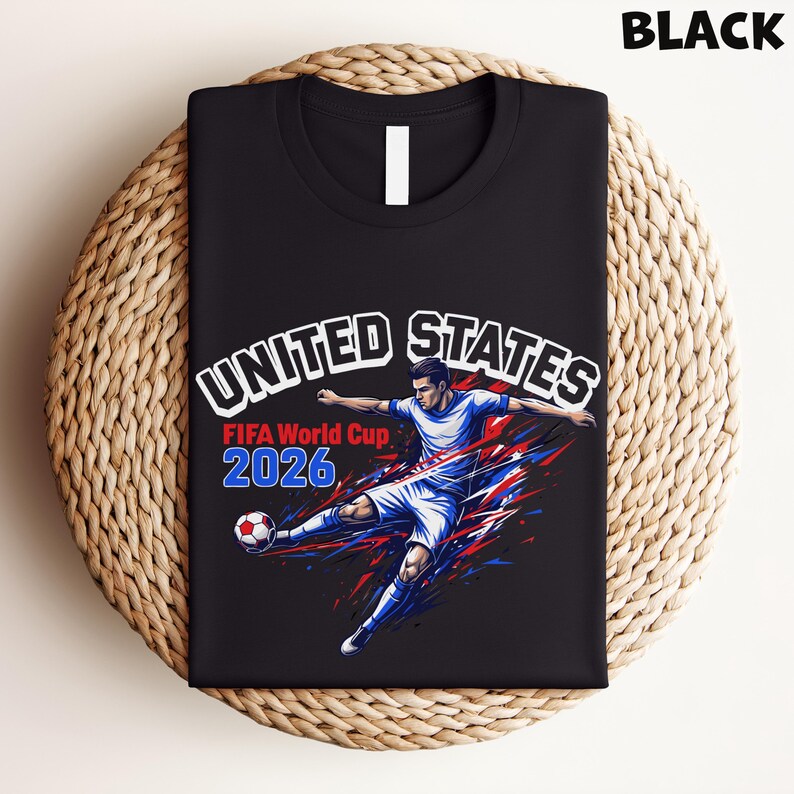 May include: Black t-shirt featuring a soccer player kicking a ball, with "UNITED STATES" and "FIFA World Cup 2026" text in white, red, and blue. The design has a dynamic, action-oriented style.
