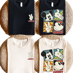 May include: Four t-shirts, two black and two off-white, are displayed. Each shirt features a Mickey Mouse design. Two shirts have a peace sign with the word "Mickey". The other two shirts have a Mickey Mouse graphic with the word "Mickey".