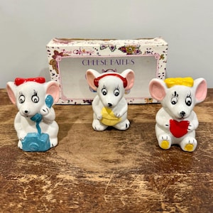 May include: A set of three ceramic vases in varying heights and shapes. The vases are glazed in a matte white finish, offering a minimalist aesthetic. The tallest vase is approximately 10 inches high.