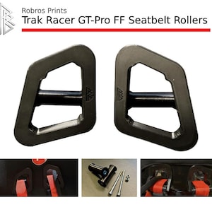 May include: Two black Trak Racer GT-Pro FF Seatbelt Rollers with a distinctive geometric shape. The product name is displayed in red text above the rollers. Additional images show the rollers installed and related hardware.