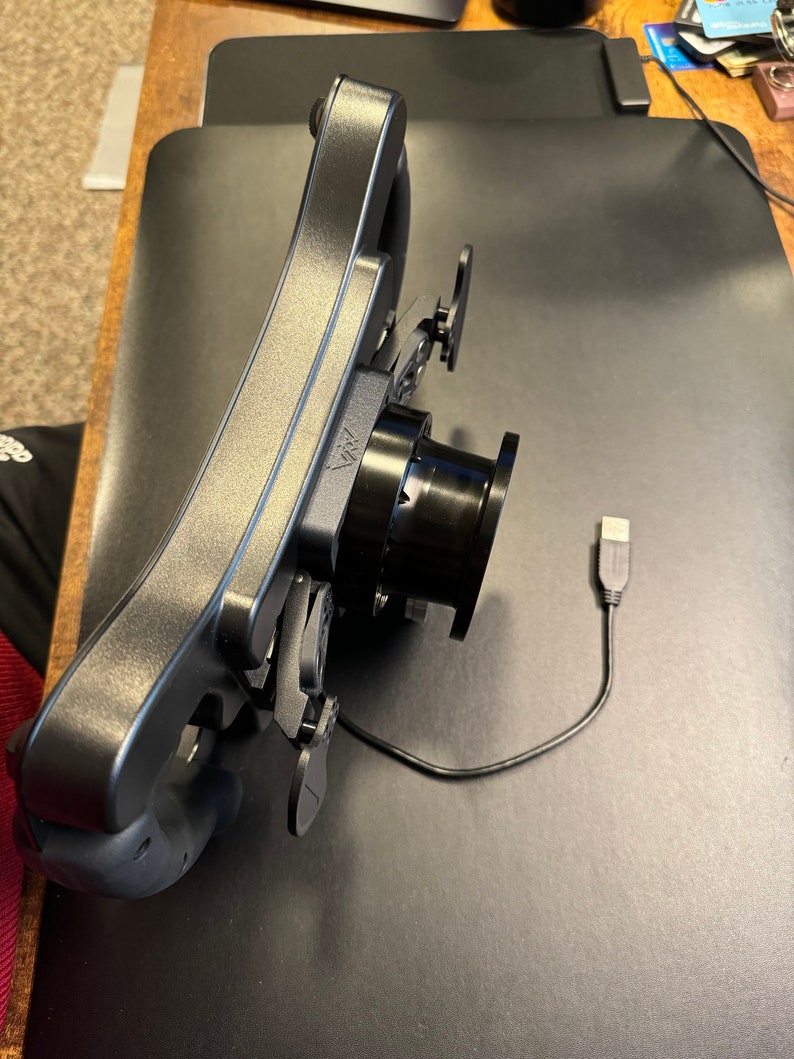 Puede incluir: Un volante de carreras negro y gris con levas de cambio y un cable USB. El volante tiene un cubo central y un dise&ntilde;o curvo para agarrar. El volante est&aacute; dise&ntilde;ado para usar con una computadora o consola de juegos.