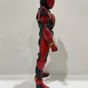 May include: A red and black action figure of a superhero with a winged helmet. The figure is posed with one leg forward and one arm raised.