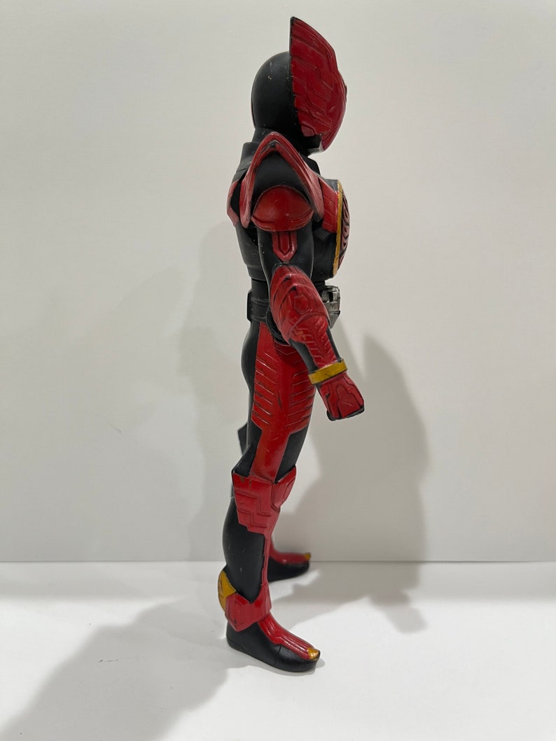 May include: A red and black action figure of a superhero with a winged helmet. The figure is posed with one leg forward and one arm raised.