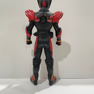 May include: Black and red action figure with a black helmet and gold accents. The figure is standing with its back to the camera.