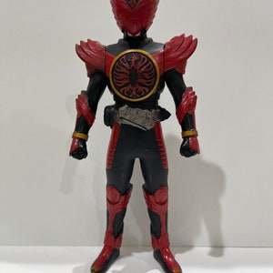 May include: A red and black action figure of a superhero with a bird-like helmet and a large red chest plate with a gold trim. The figure is standing on a white background.