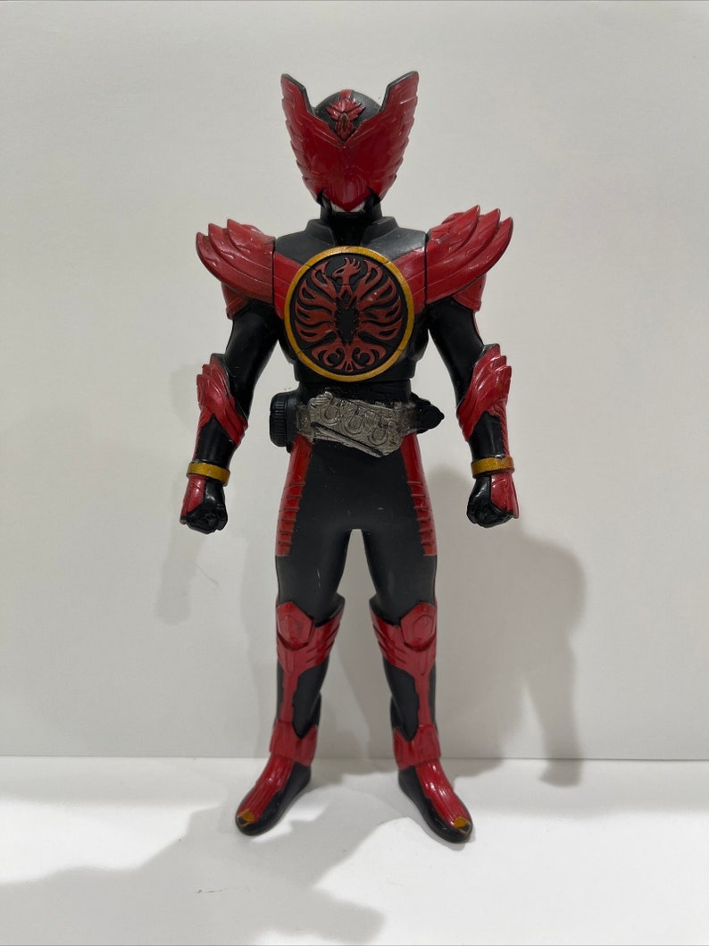 May include: A red and black action figure of a superhero with a bird-like helmet and a large red chest plate with a gold trim. The figure is standing on a white background.