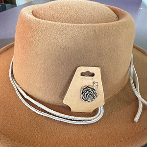 May include: A brown felt fedora hat with a white cord and a small rose-shaped pin attached to a brown tag that says "#7".