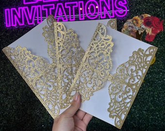 May include: White invitation cards with intricate gold glitter lace cutouts. The cards are held in front of a neon sign that reads "BELLA INVITATIONS". The design features a decorative floral pattern.