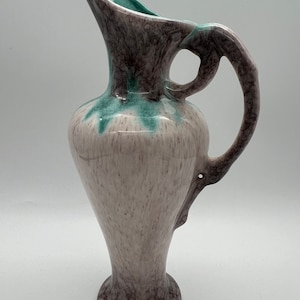 Può includere: Un'anfora in ceramica con una glassa rosa chiaro e un design marmoreo verde e viola. L'anfora ha una bocca larga e un manico.