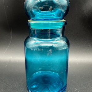 Könnte beinhalten: Eine große, blaue Glasdose mit einem abgerundeten Deckel. Die Dose ist klar und hat eine strukturierte Oberfläche.
