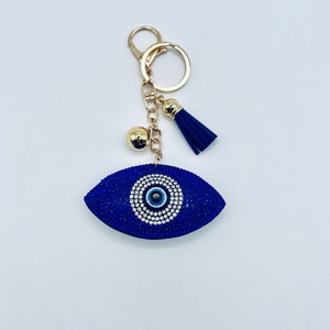 May include: A blue evil eye charm keychain with rhinestones and a gold chain with a tassel.