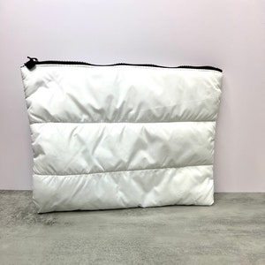 May include: White quilted zippered pouch with a black zipper.