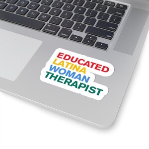 Può includere: Un adesivo bianco su un laptop con le parole "EDUCATED LATINA WOMAN THERAPIST" in rosso, giallo, blu e verde. L'adesivo è su un laptop argentato.