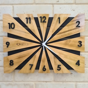 May include: A wooden clock with black and brown stripes and black numbers. The clock face is a sunburst design with white hands.