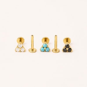 May include: Three gold-tone flat back stud earrings, each featuring a cluster of three small stones arranged in a triangle. One earring has clear white stones, one has bright blue turquoise stones, and one has dark black stones.