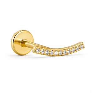 May include: A gold flat back labret stud featuring a curved bar design. The front of the curved bar is set with a row of ten small, clear, round-cut stones. The piece has a polished gold finish and a circular flat base at the end of the post.