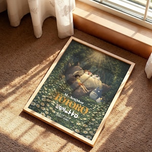 K&ouml;nnte beinhalten: Ein gerahmter Druck des Animationsfilms "Mein Nachbar Totoro" mit den Charakteren Totoro, Mei und dem Katzenbus. Das Kunstwerk spielt in einem Wald mit einem Feld wei&szlig;er Blumen, mit dem Titel in goldfarbenen Buchstaben.