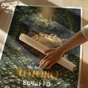 K&ouml;nnte beinhalten: Eine gerollte Poster des Zeichentrickfilms "Mein Nachbar Totoro". Das Poster zeigt eine Szene mit Totoro, Kindern und kleinen wei&szlig;en Kreaturen in einer Waldlandschaft. Der Titel "TOTORO" ist in goldfarbenen Buchstaben, darunter japanischer Text.