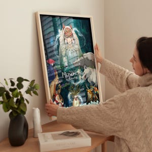 K&ouml;nnte beinhalten: Gerahmter Kunstdruck mit dem Anime-Film "Prinzessin Mononoke". Das Kunstwerk zeigt Charaktere und Szenen aus dem Film, wobei der Titel im Mittelpunkt steht. Der Druck befindet sich in einem Holzrahmen.