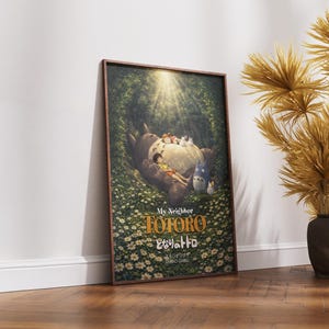 K&ouml;nnte beinhalten: Gerahmtes Poster mit dem Zeichentrickfilm "Mein Nachbar Totoro". Das Kunstwerk zeigt Totoro mit Kindern in einer Waldszene, mit dem Filmtitel in goldfarbenen Buchstaben. Das Poster wird vor einer wei&szlig;en Wand und einem Holzboden pr&auml;sentiert.