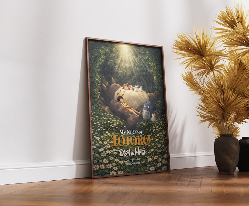 K&ouml;nnte beinhalten: Gerahmtes Poster mit dem Zeichentrickfilm "Mein Nachbar Totoro". Das Kunstwerk zeigt Totoro mit Kindern in einer Waldszene, mit dem Filmtitel in goldfarbenen Buchstaben. Das Poster wird vor einer wei&szlig;en Wand und einem Holzboden pr&auml;sentiert.