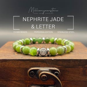 Puede incluir: Una pulsera de jade nefrita con cuentas de 7,5 mm y un acento de acero inoxidable. La pulsera presenta un dije plateado con la letra "Z". La pulsera se exhibe en una caja de madera.