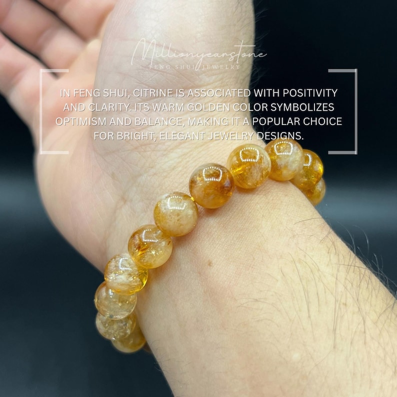 May include: A bracelet of golden citrine beads. The beads are round and have a warm, amber color. The bracelet is worn on a wrist. Text in the image states that citrine symbolizes optimism and balance.