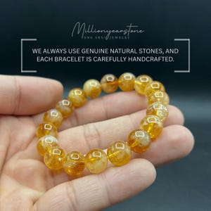 May include: A handcrafted bracelet made of golden-yellow, round natural stones. The bracelet is held in a hand against a dark background. Text in the image reads: "WE ALWAYS USE GENUINE NATURAL STONES, AND EACH BRACELET IS CAREFULLY HANDCRAFTED."