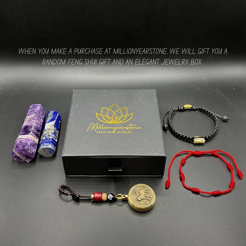 May include: An assortment of Feng Shui items, including a black jewelry box with a gold logo, two stone obelisks, two bracelets, and a charm. The text on the box reads "Millionyearstone Feng Shui Jewelry."