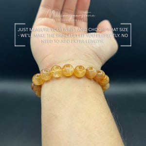 May include: A golden-yellow beaded bracelet is worn on a wrist. The bracelet is made of round, translucent beads. Text in the image reads: "JUST MEASURE YOUR WRIST AND CHOOSE THAT SIZE - WE'LL MAKE THE BRACELET FIT YOU PERFECTLY. NO NEED TO ADD EXTRA LENGTH."