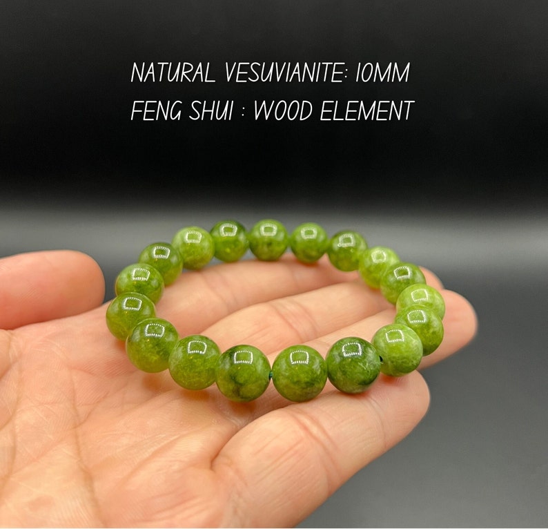 May include: A green gemstone bracelet with 10mm beads. The bracelet is made of natural Vesuvianite and is a wood element in Feng Shui. NATURAL VESUVIANITE: 10MM FENG SHUI: WOOD ELEMENT