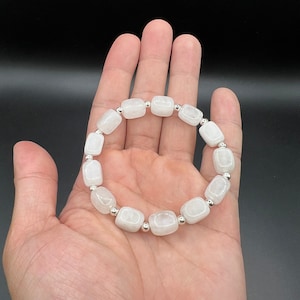 May include: White gemstone bracelet with silver beads. The bracelet is made of square-shaped stones and is strung on a silver chain.