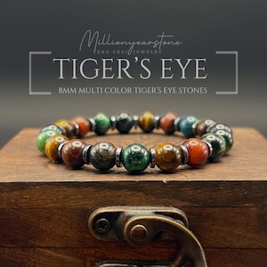 May include: A beaded bracelet featuring 8mm multi-color tiger's eye stones and small metallic spacers. The text in the image reads: Millionyearstone FENG SHUI JEWELRY TIGER'S EYE 8MM MULTI COLOR TIGER'S EYE STONES. The stones are round and polished.
