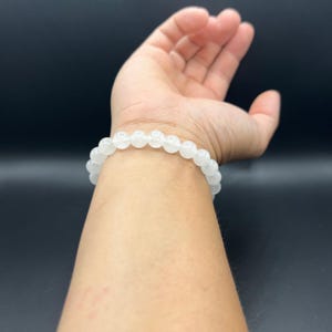 Op de afbeelding: Een witte kralen armband met ronde kralen.