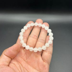Op de afbeelding: Witte kristallen kralen armband met ronde kralen. De armband is gemaakt van natuurlijke stenen en is ongeveer 18 cm lang.