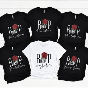 Puede incluir: Seis camisetas negras con una mano de esqueleto blanca sosteniendo una rosa roja y el texto "RIP to her last name" y una camiseta blanca con el mismo diseño pero el texto "RIP single life".
