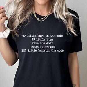 Peut inclure: T-shirt noir avec un texte blanc qui dit "99 little bugs in the code, 99 little bugs, Take one down, patch it around, 127 little bugs in the code".