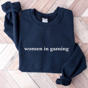 May include: A navy blue sweatshirt with the text "women in gaming" printed in white on the front.