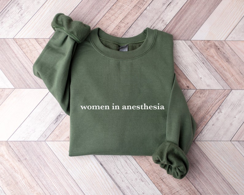 Peut inclure: Un sweat-shirt vert avec le texte "women in anesthesia" imprim&eacute; en blanc sur le devant.