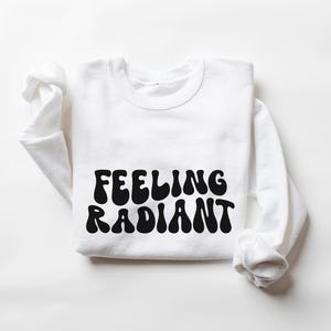 a white sweatshirt with the words feeling radiant printed on it