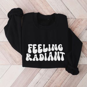 a black sweatshirt with the words feeling radiant printed on it