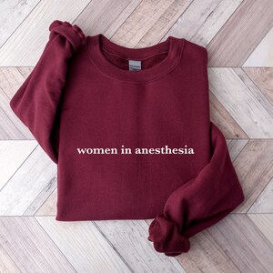 Peut inclure: Sweat-shirt bordeaux avec le texte "women in anesthesia" imprim&eacute; en blanc.